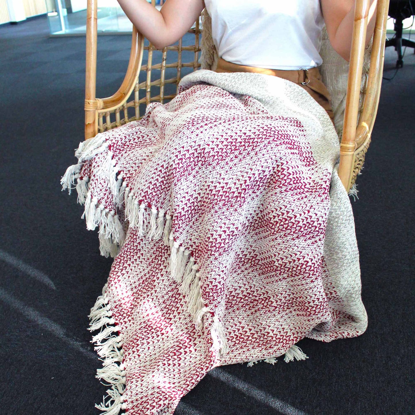 Person sitting on a chair with a red and white patterned blanket draped over their lap.